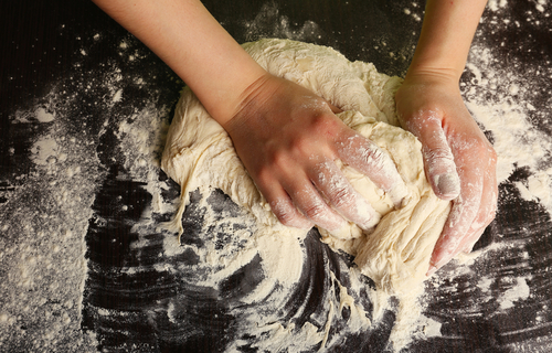A young girl's hands knead bread dough. This shows the every day grounding activities that bring healing to children in foster care.